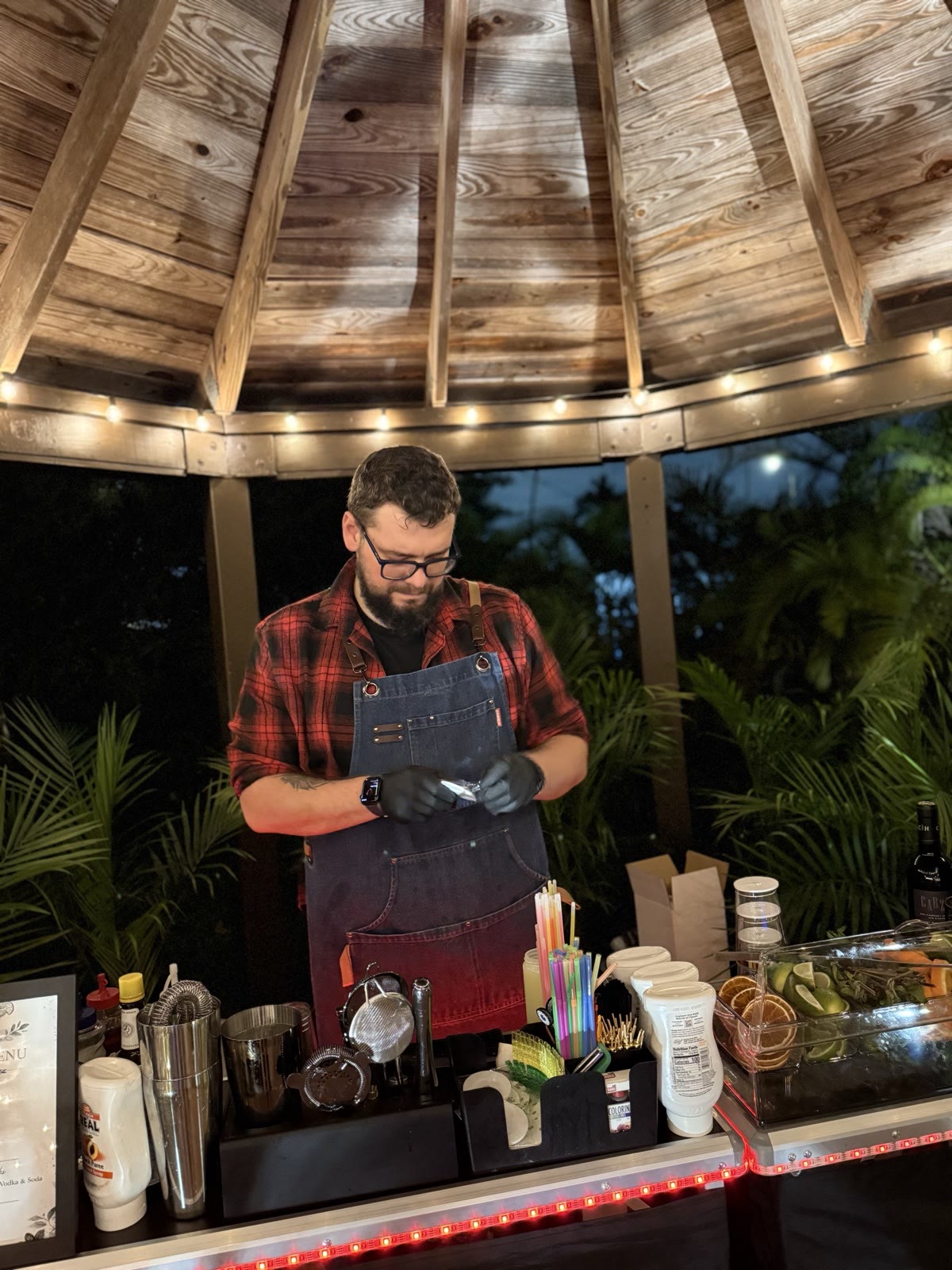 Bartender under gazebo preparing drinks at night Miami