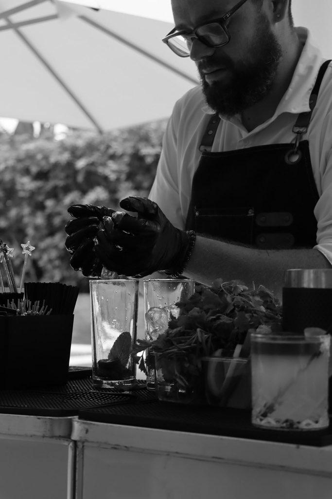 Black and white photo of Miami bartender muddling cocktails behind the bar