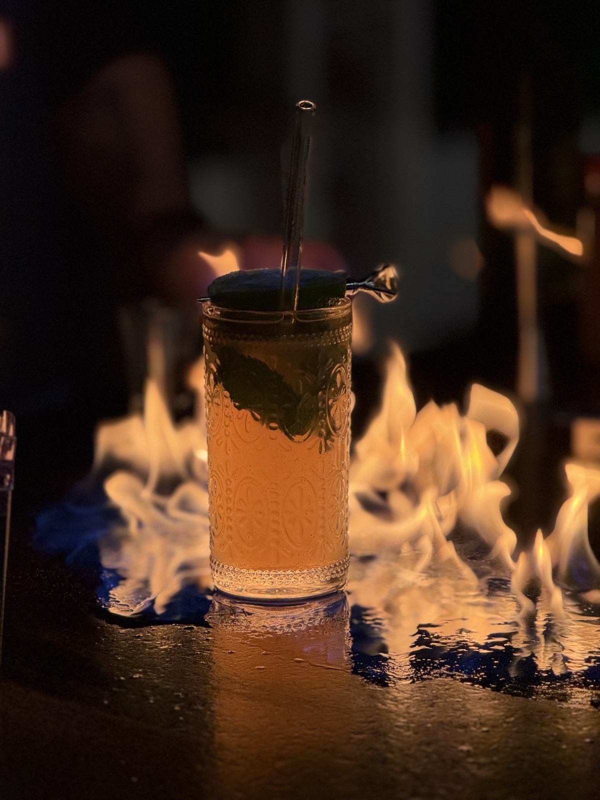 Single cocktail surrounded by flames on bar Miami
