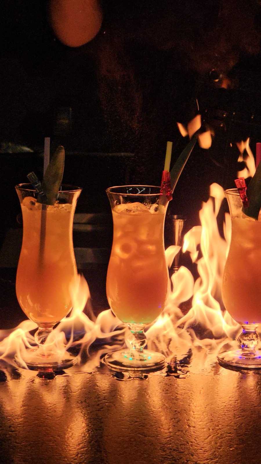 Three flaming cocktails lined up on bar Miami