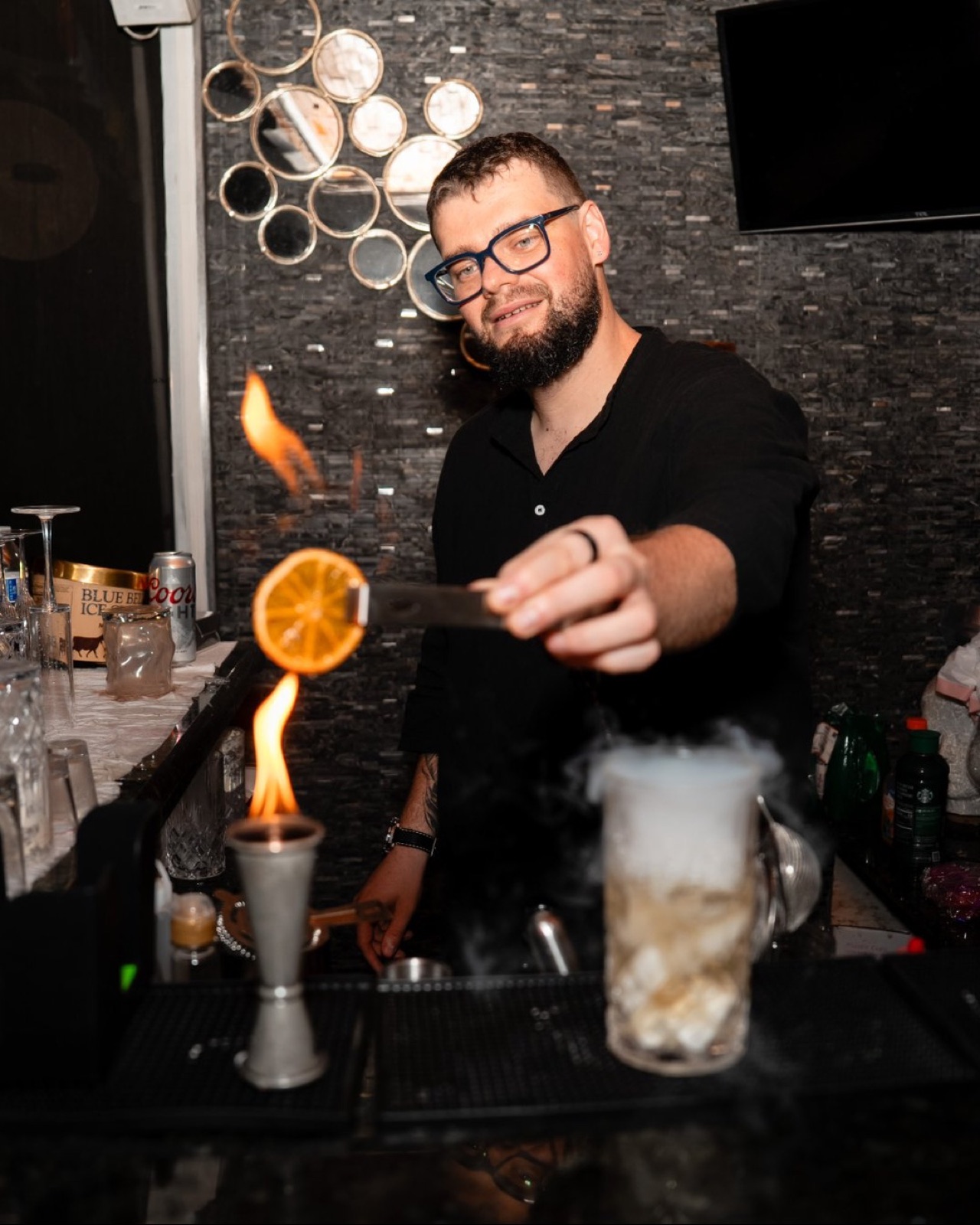 Bartender flambeing orange slice for cocktail Miami